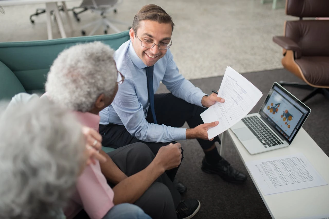 A financial advisor in a modern office, explaining a financial plan to a young couple. The advisor is pointing to a chart on a tablet, and the couple looks engaged and confident.