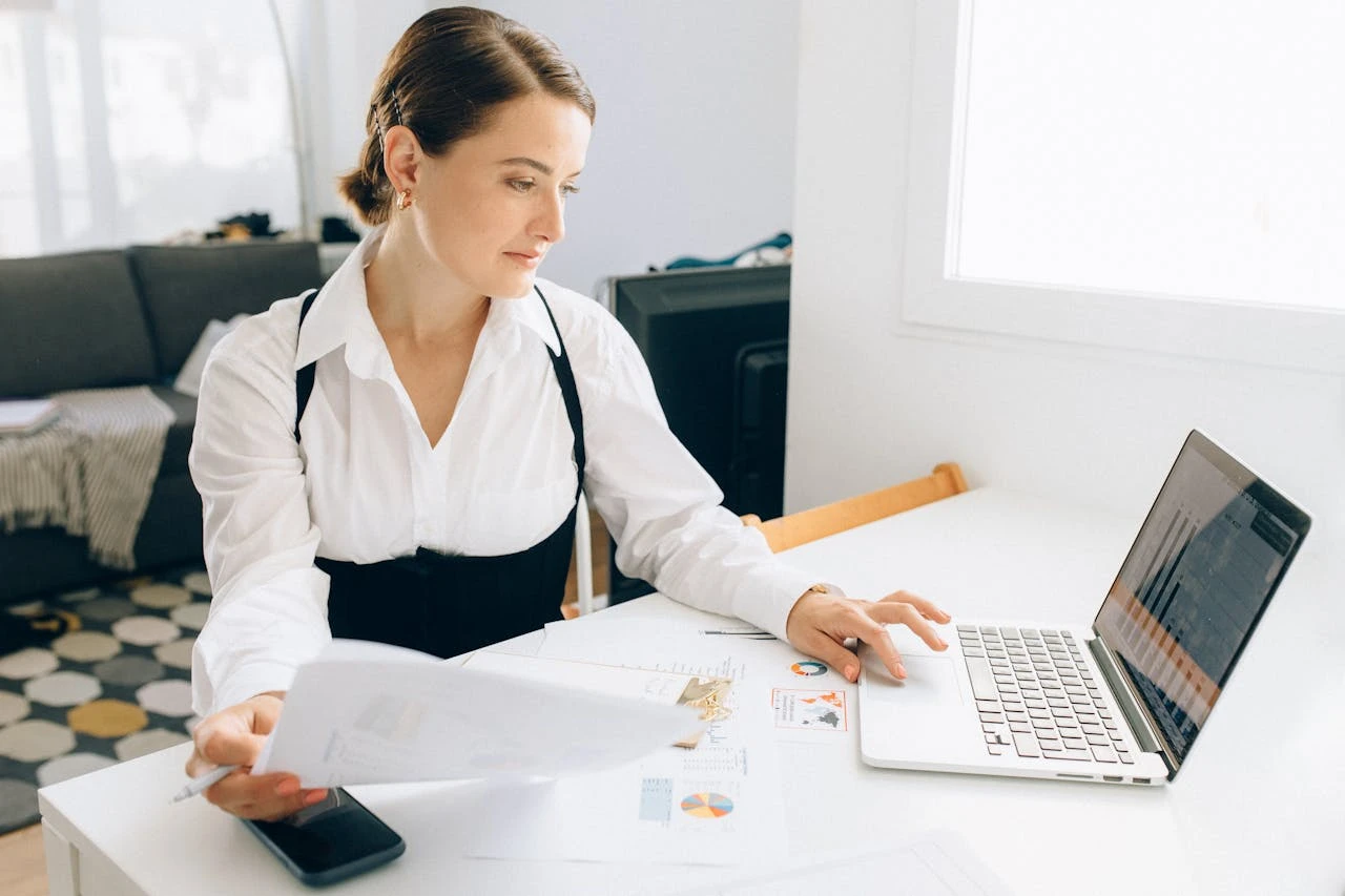 Image of a young professional analyzing financial data on a laptop with charts and graphs visible on the screen.